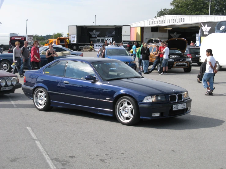 a car parked in a parking lot with people surrounding