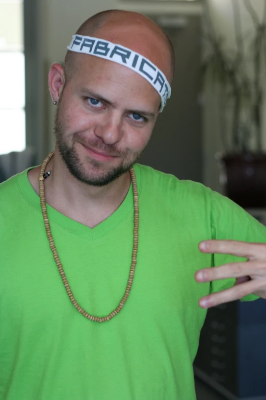 a bald man wearing a neon green shirt with a funny hat on top of his head