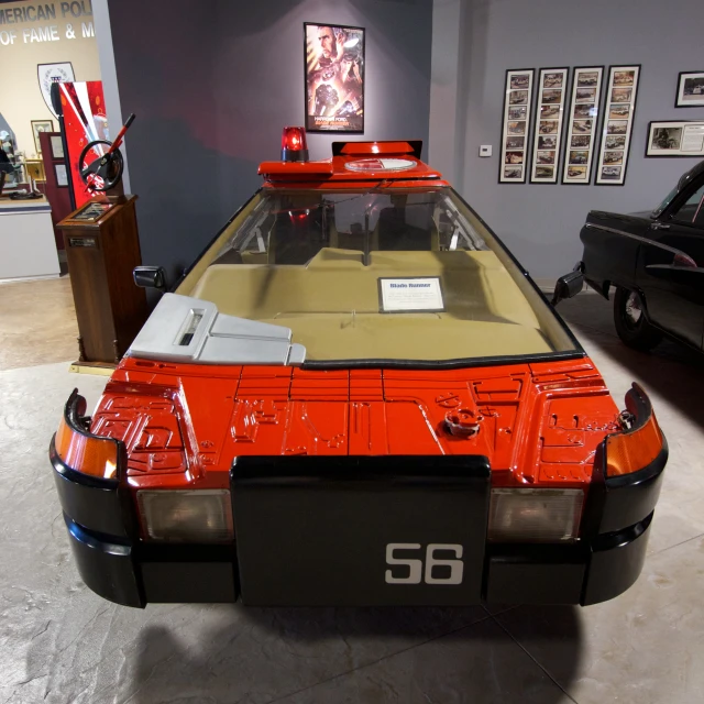 an orange car in a garage with a sign on top