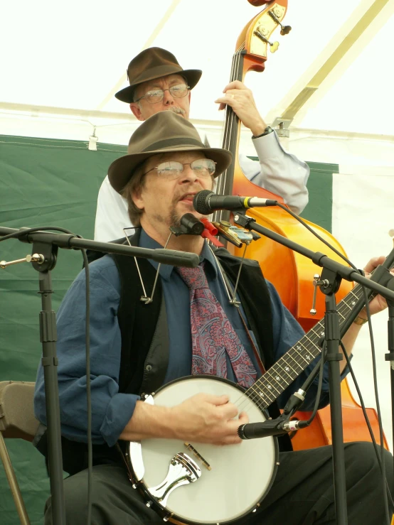 two people with hats playing an instrument at an outdoor concert