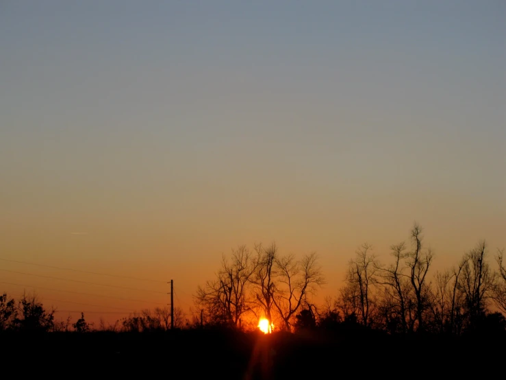 a sunset with trees silhouetted against the horizon