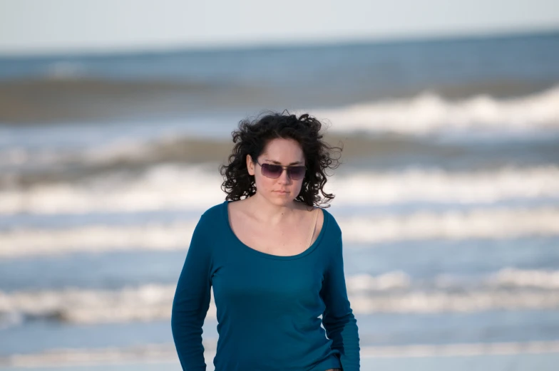 the woman in the blue shirt is walking on the beach