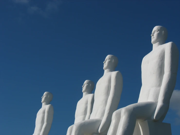 three statues are shown against a blue sky