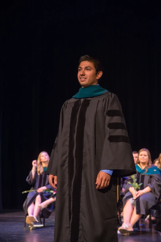 a young graduate poses with other graduates on stage