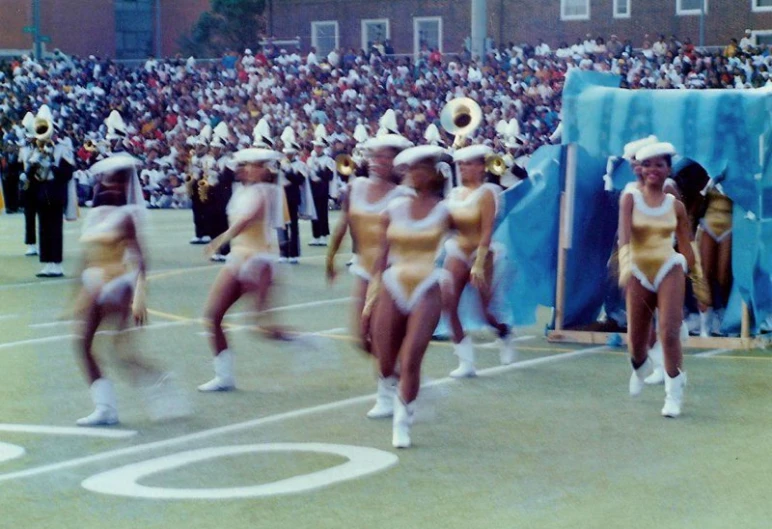 a parade of cheerleaders walking in formation in front of a crowd