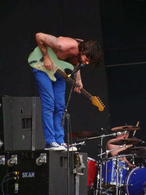 a man with his shirt off playing a guitar on stage