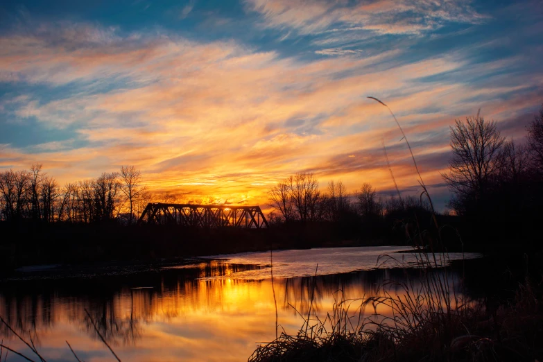 the sun is setting over the water near some trees