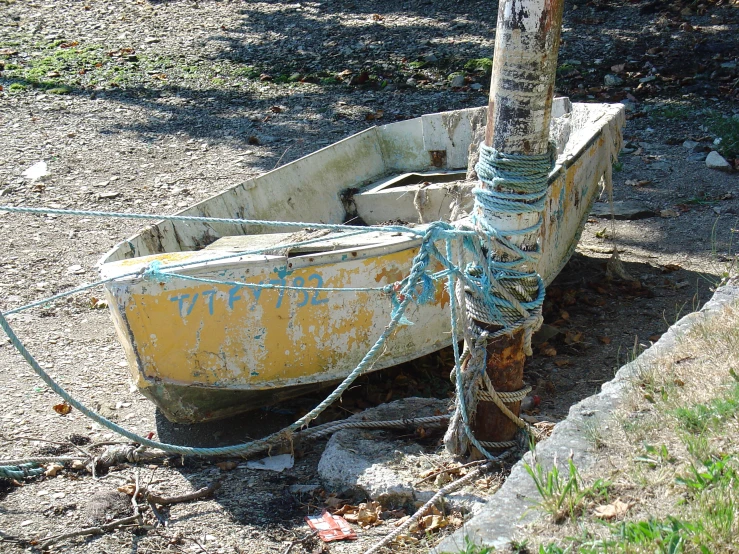 a roped up yellow dingy boat sitting in the sand