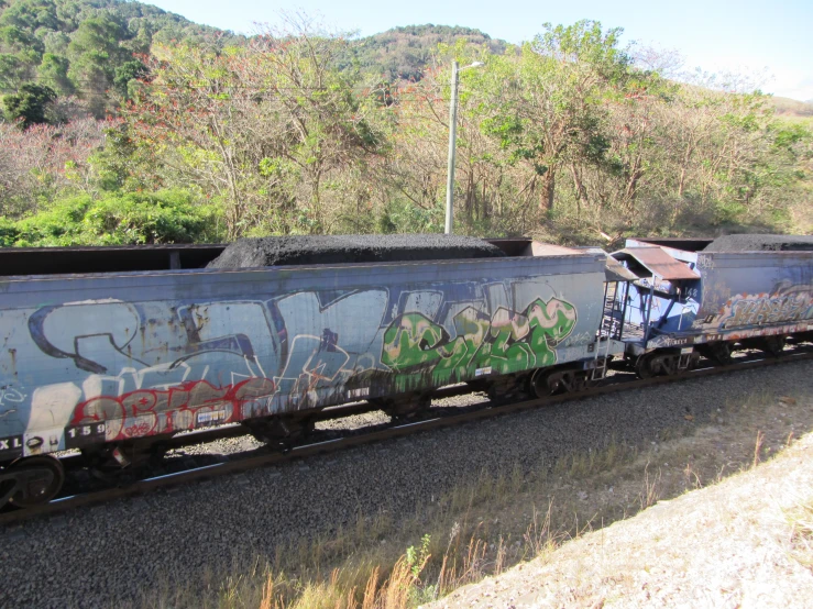 there is a train with graffiti on it going by the mountain