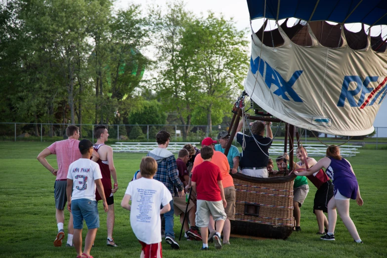 children in a field watching another group unveil a large balloon