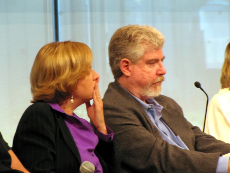 a man and woman sitting together in front of microphones