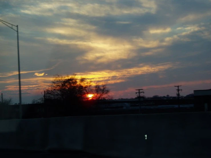 the sun rises over a freeway as it passes through a power station