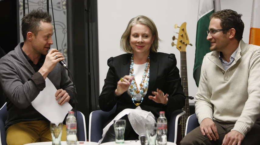 two men and one woman sit at a table