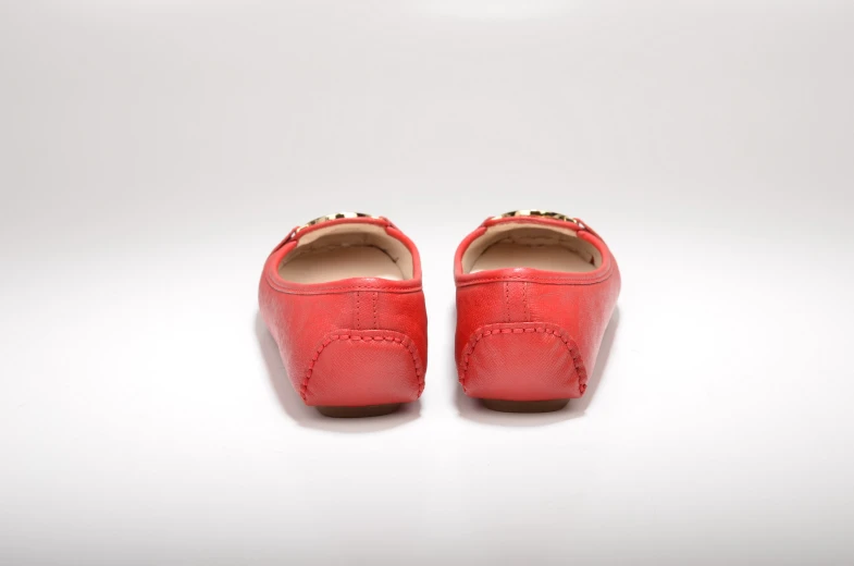 a pair of shoes in red leather sitting on top of a white floor