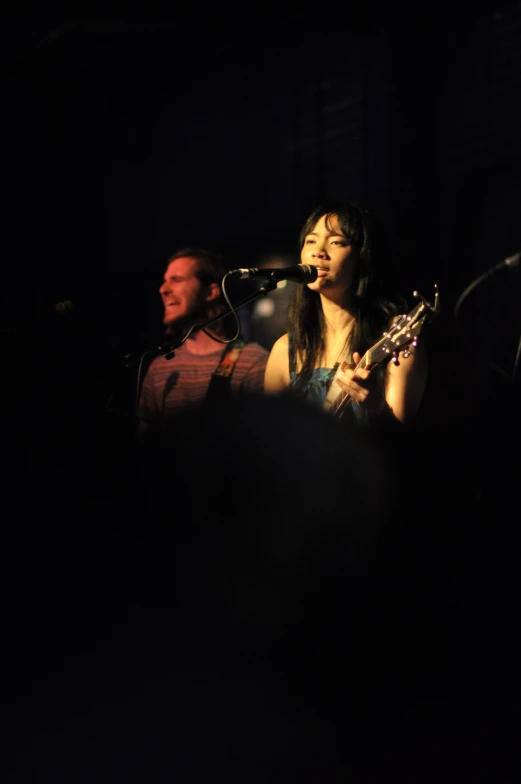 woman with guitar in front of audience at concert