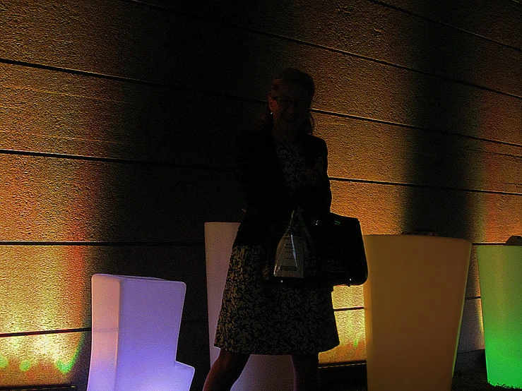 a woman standing in front of lights holding a bag
