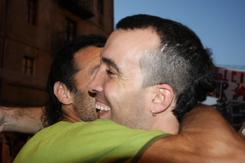 a smiling man hugging another mans neck and forehead