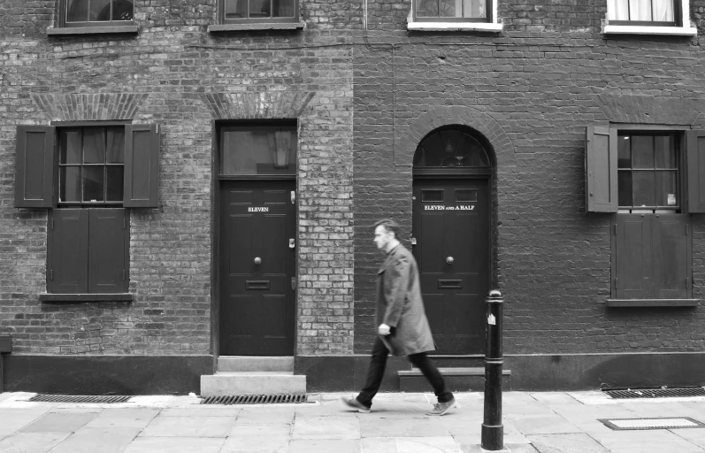 a man walking down a sidewalk near a black door