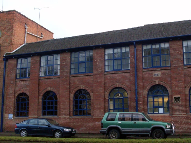 two vehicles parked in front of a large red brick building