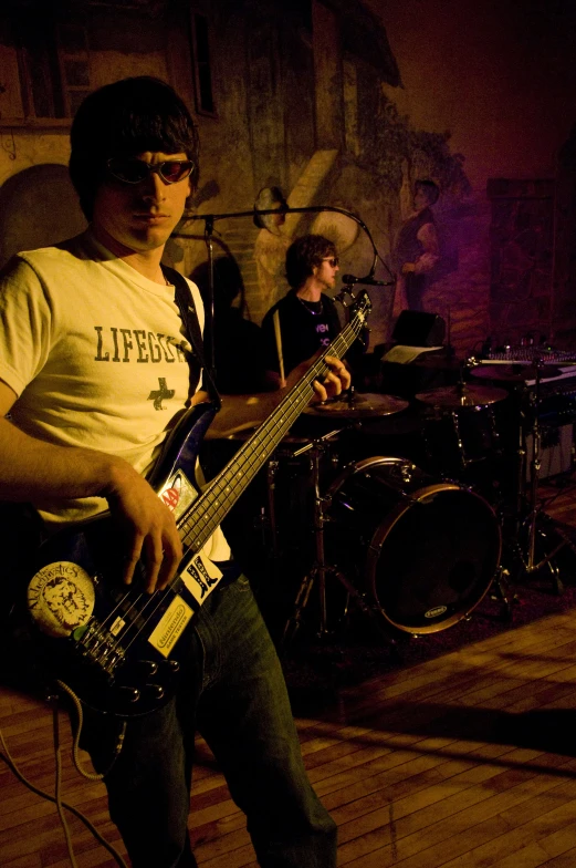 a man in a t - shirt standing next to a band playing music