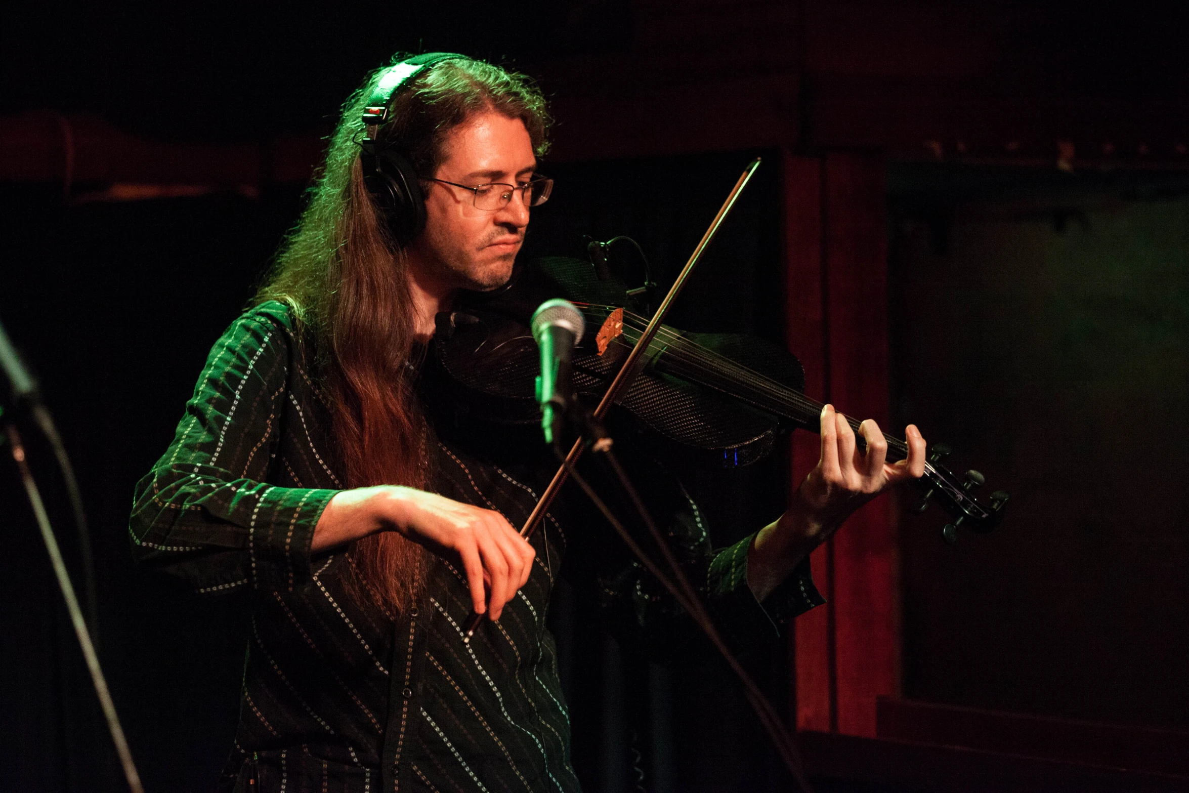 a woman playing violin while looking at the microphone