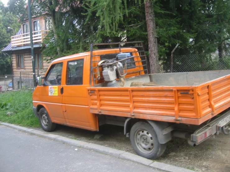 an orange truck is parked next to a tree