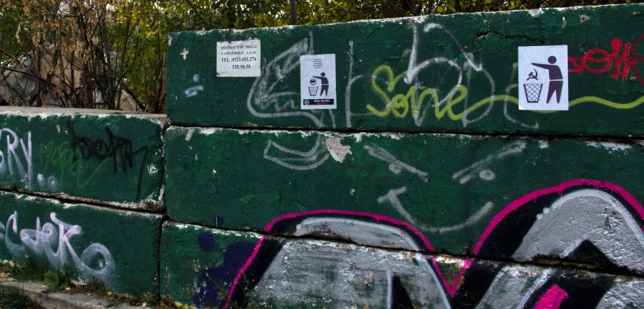 graffiti on an old stone wall along a paved area