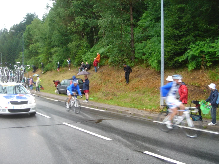 bicyclists cross the street as cars pass by on a crowded road