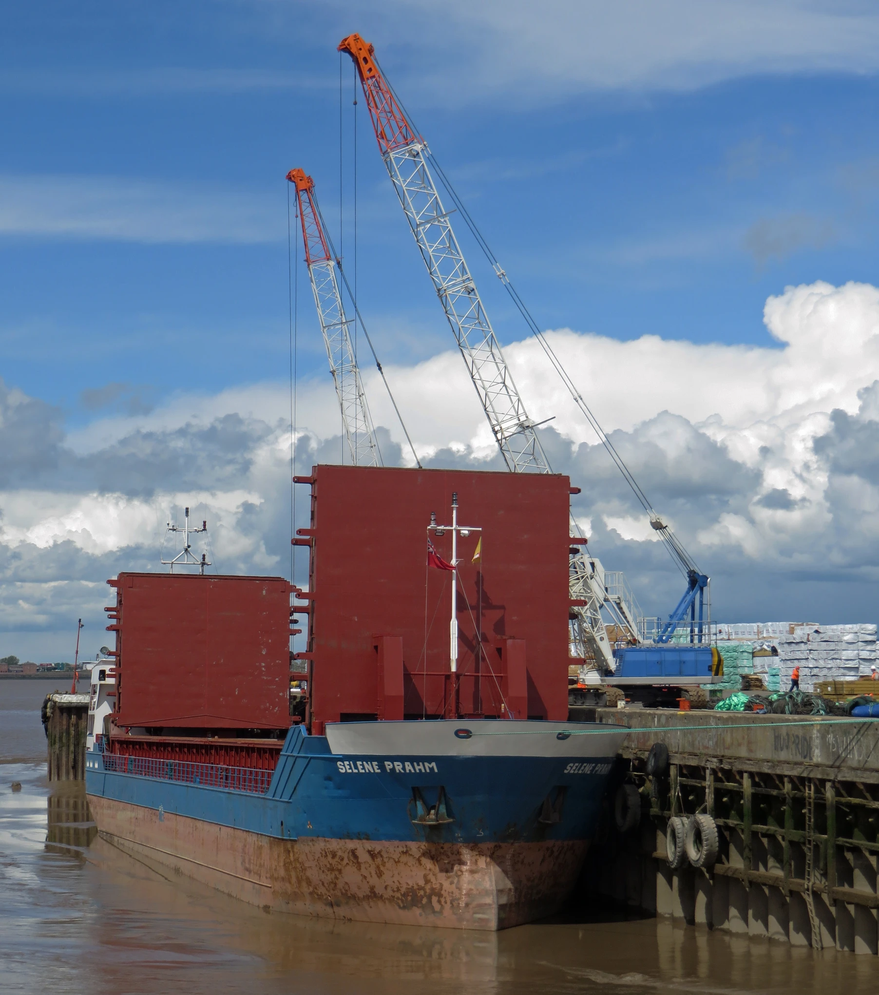 a boat docked near a pier and with cranes