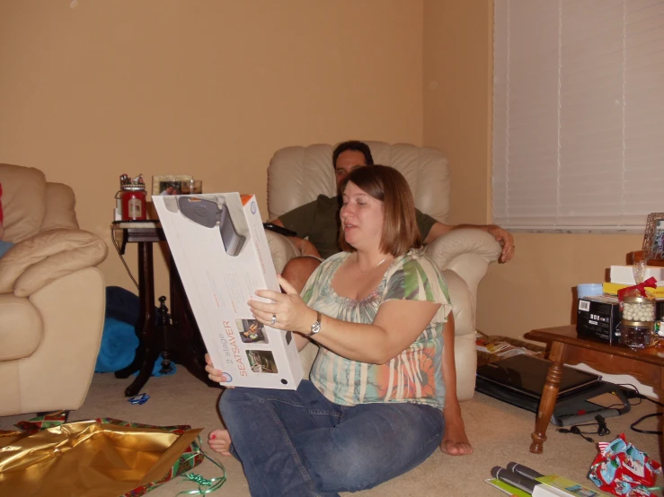 a woman sitting on the floor holding a box with some wrapping