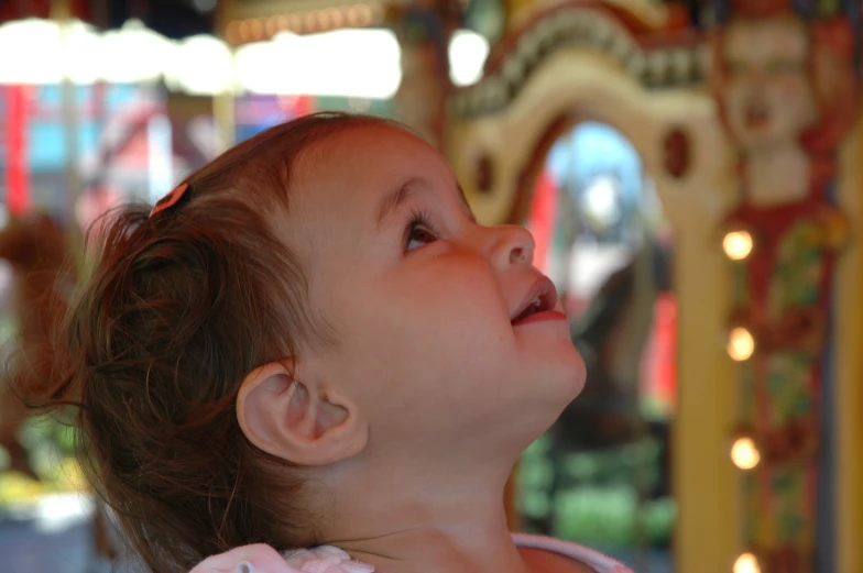 a small girl is at a carnival park looking up