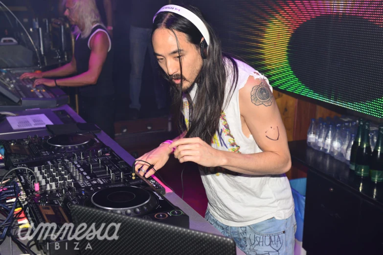 man with headphones standing behind dj equipment at party