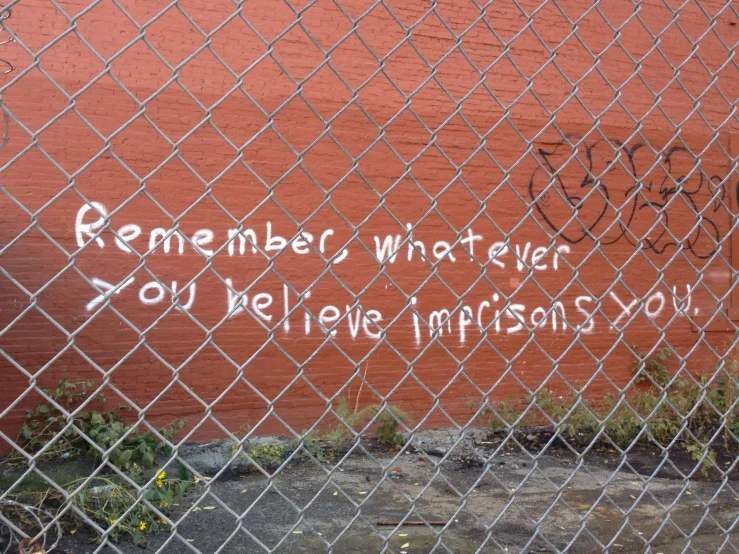 the back part of a graffiti - covered fence with graffiti on it and words written in white