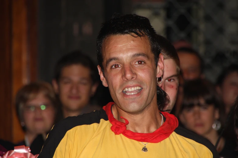 a man in a yellow shirt is smiling while others watch