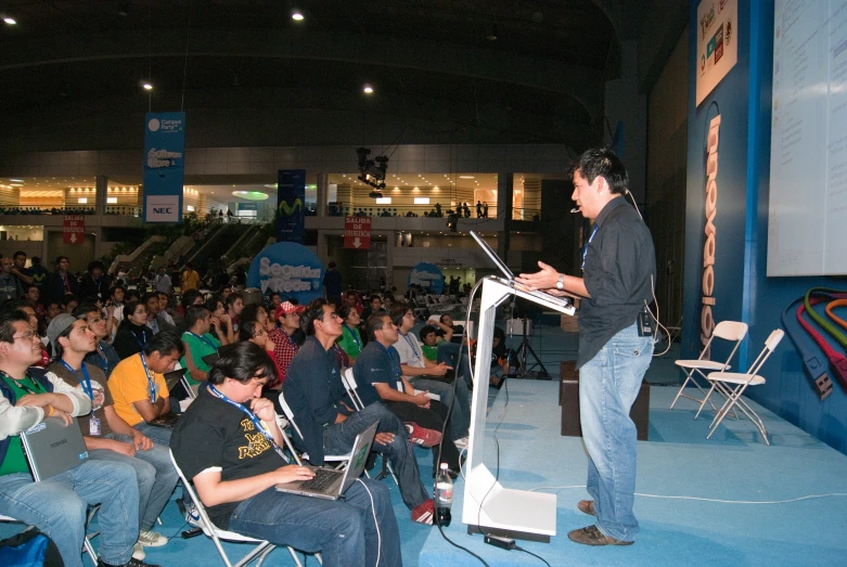 a man standing in front of a crowd holding a laptop computer