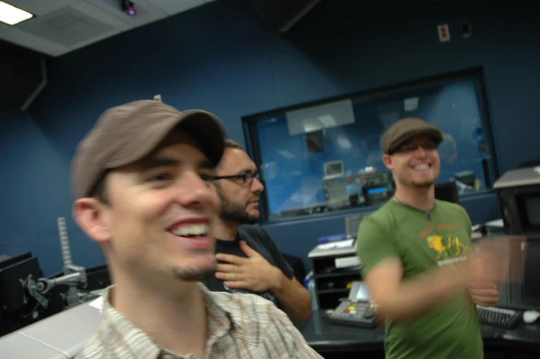 two men smile and laugh in a room filled with computers