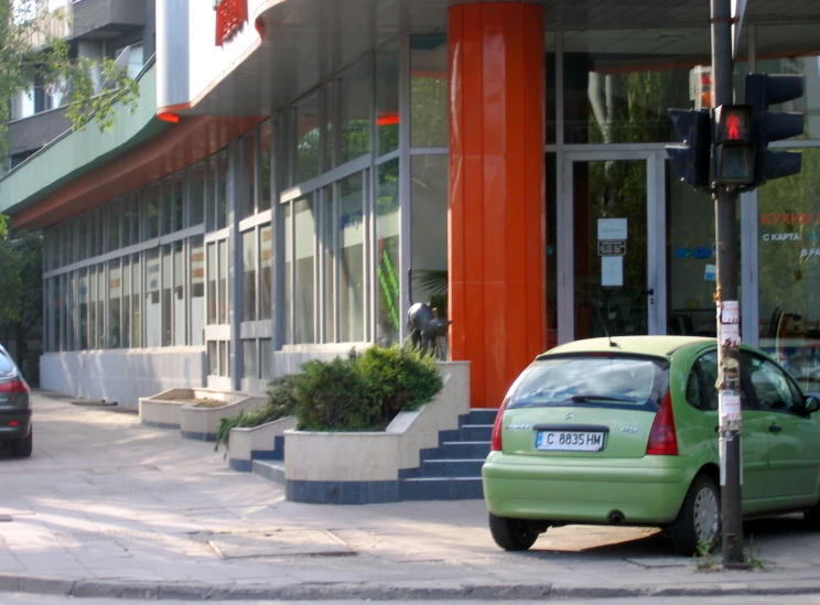 a car parked on the side of a street near tall windows