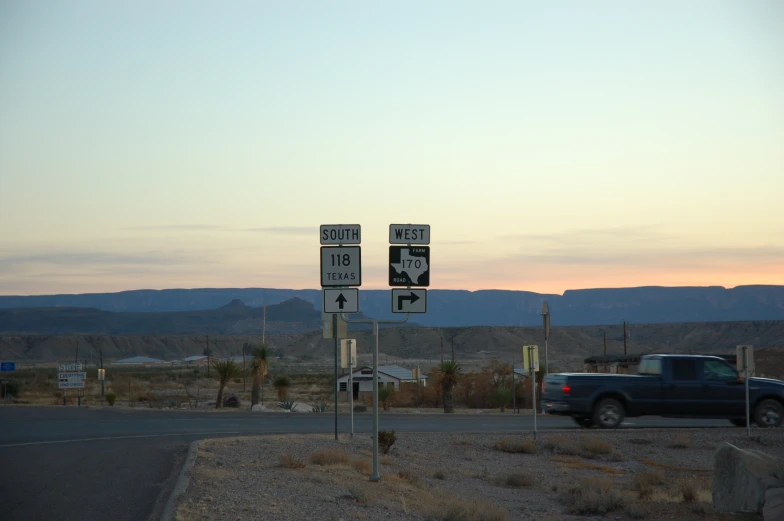 three signs next to a road on an open desert field