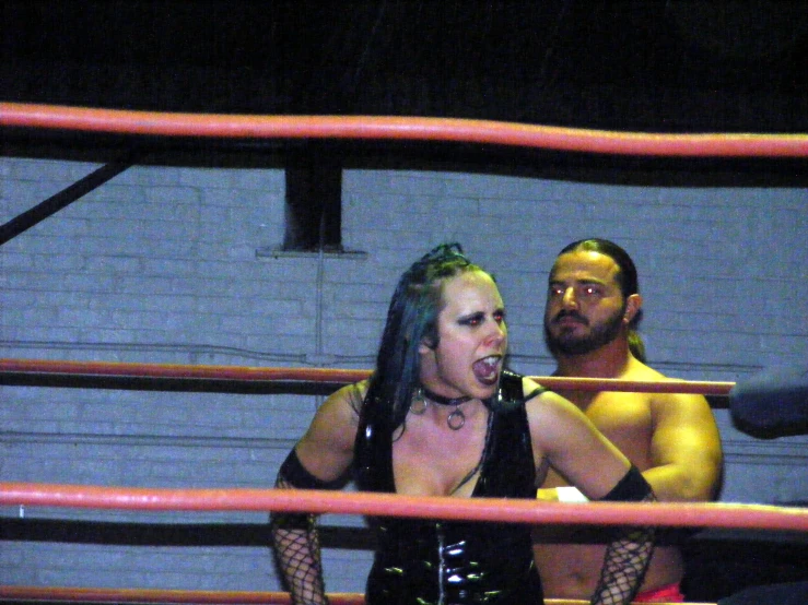 a woman with very long hair standing next to a wrestler