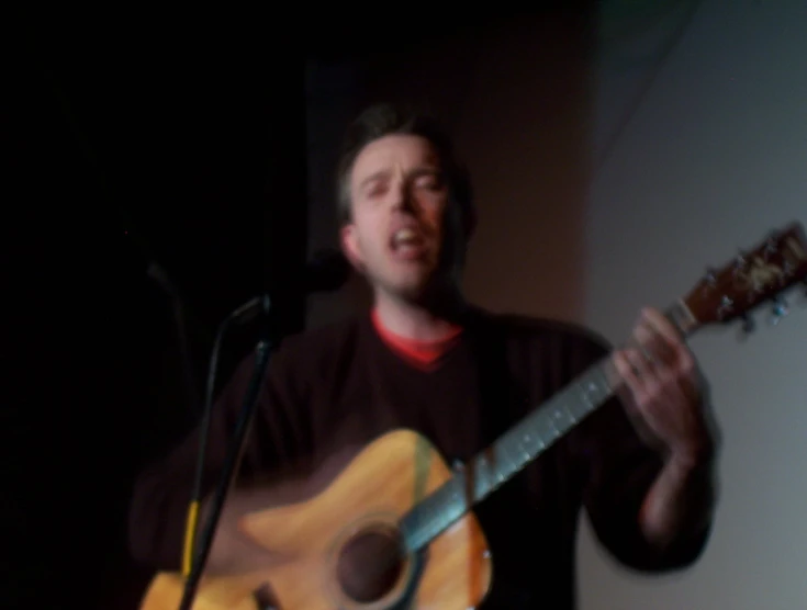 a man holding an acoustic guitar while singing