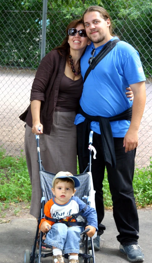 a man, woman and a boy stand beside each other with a stroller