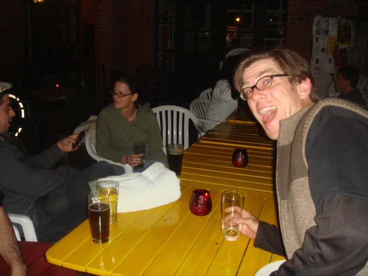 a man and two women sitting at a table with drinks in their hands