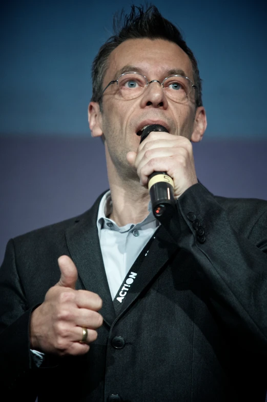 a man in glasses holding up his microphone