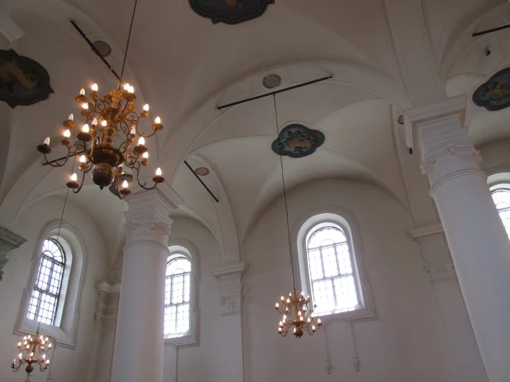 an elegant white and gold chandelier hangs from the ceiling in the white painted room