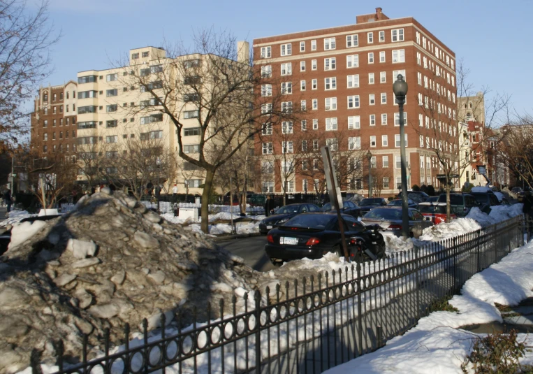 many cars are parked along the street near a building