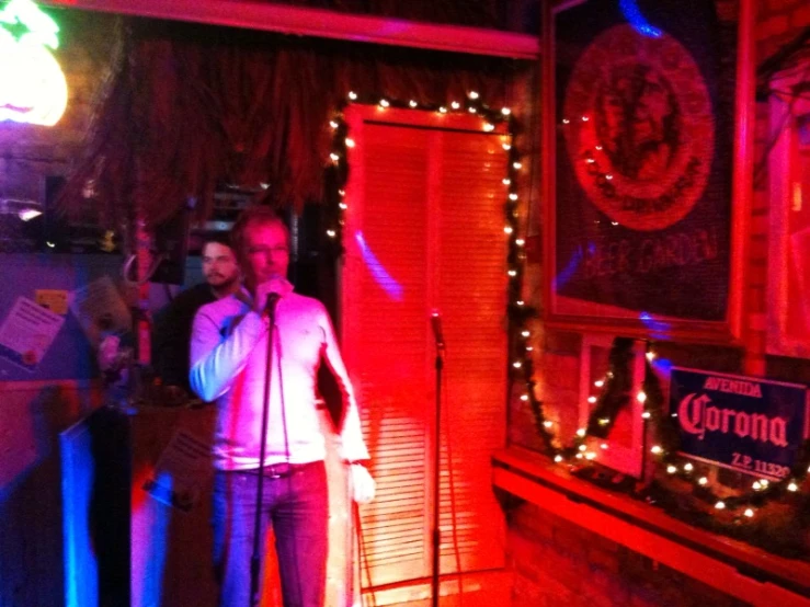 a man singing at a microphone in a room decorated with lights