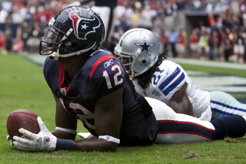 two football players are laying on the ground with their helmets on