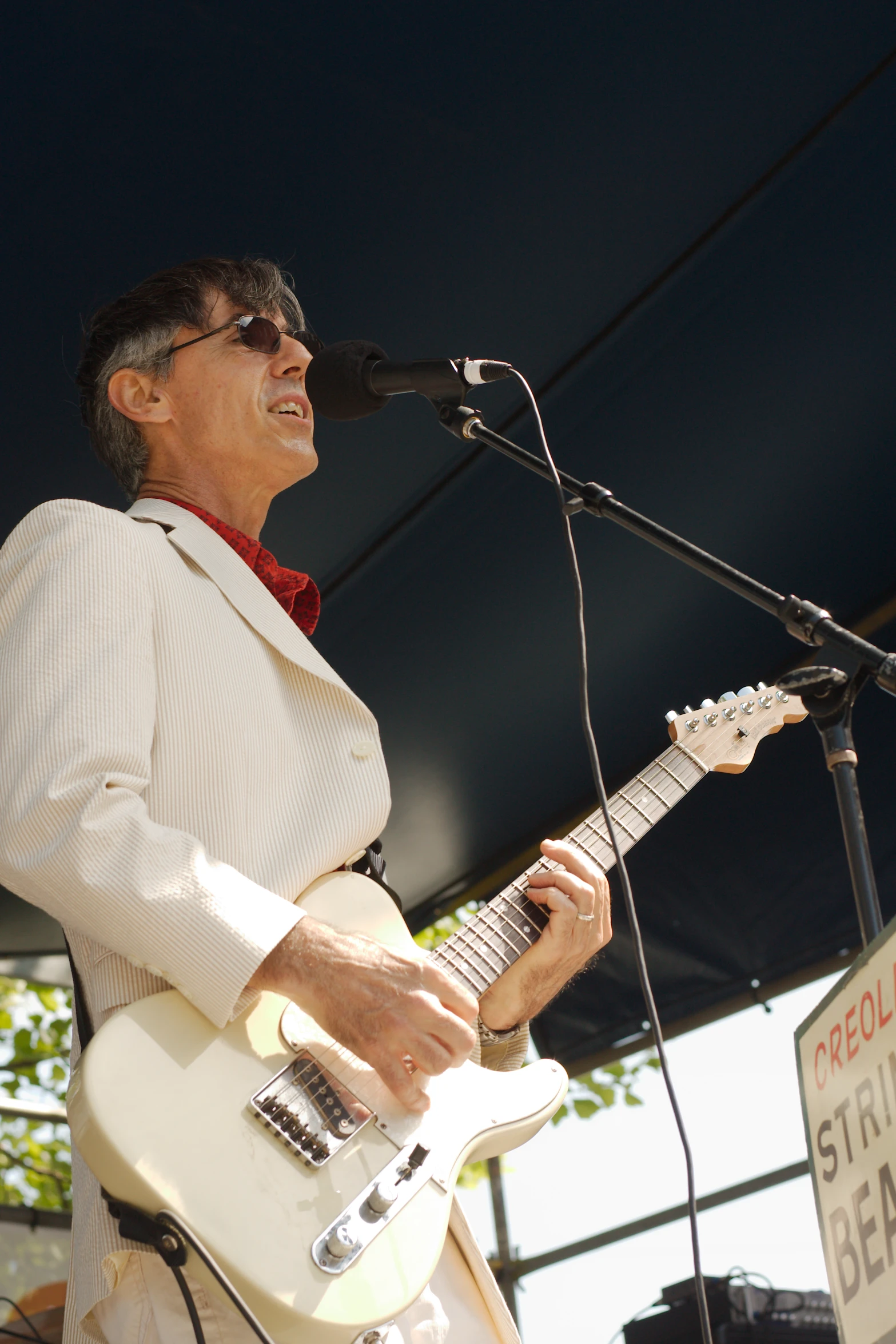 a man standing next to a microphone with a white guitar
