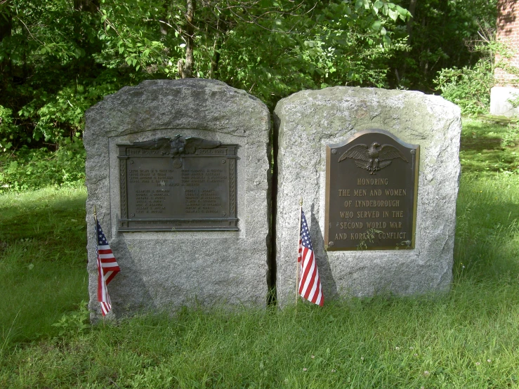 there are two plaques on the grass near flags