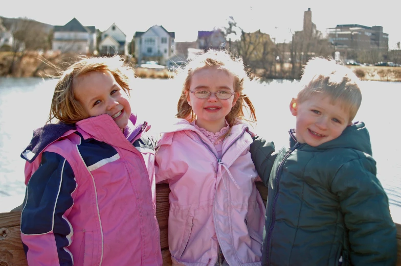 three little s pose for a po in front of a lake